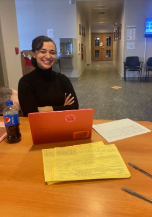 Ellyana, the greeter, sits at a table smiling